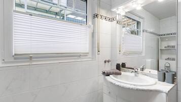 Une salle de bain avec un lavabo blanc, un miroir et un porte-serviettes.
