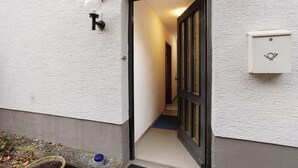 Ein schmaler Korridor mit einer Tür am Ende, einer Wandleuchte und einem Briefkasten.