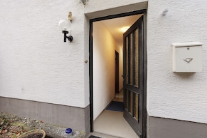 A narrow hallway with a door at the end, a light fixture on the wall, and a mailbox. - Apartment 'Ferienwohnung, 60qm' with Shared Terrace, Private Garden and Wi-Fi (Balve)