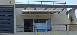 A modern building with a covered entrance, a metal railing, and a large fan. - Évasion vue mer à Farinole - 15 m² terrace, 2 minutes from the beach (Farinole)