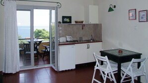 Une cuisine compacte avec un coin repas, une vue sur la mer et une porte-fenêtre coulissante.