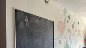 Une salle de classe avec un tableau noir, une gomme pour tableau et une fresque murale.