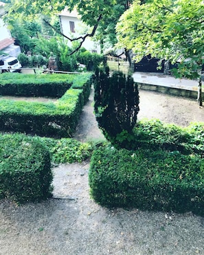 A garden with neatly trimmed hedges, a gravel path, and a building in the background. - Villino Serena Di Lapigio Florence: Mountain View, Private Garden (Saltino)