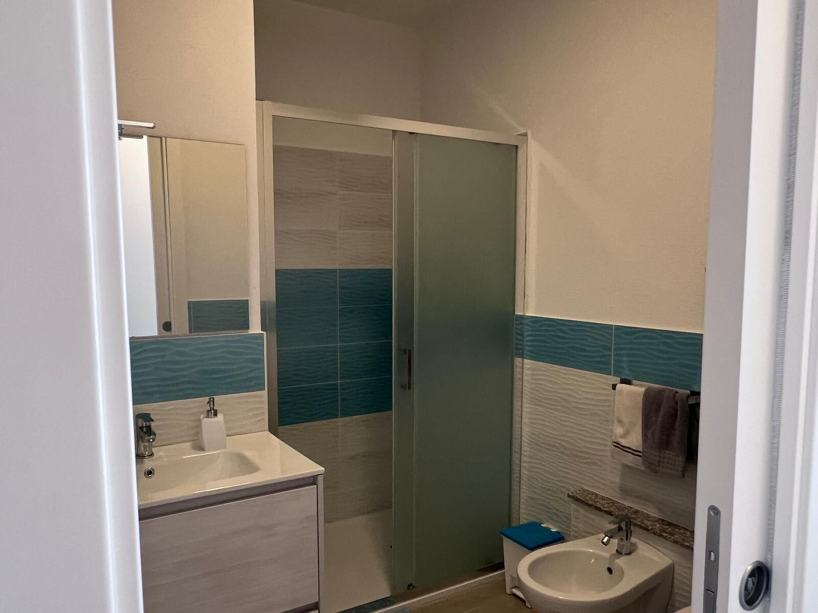 A bathroom with a shower, sink, and mirror.