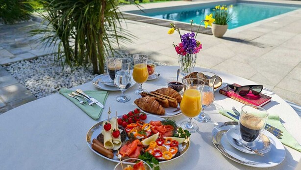 Una mesa lista para el desayuno con cruasanes, salmón ahumado y fruta fresca.