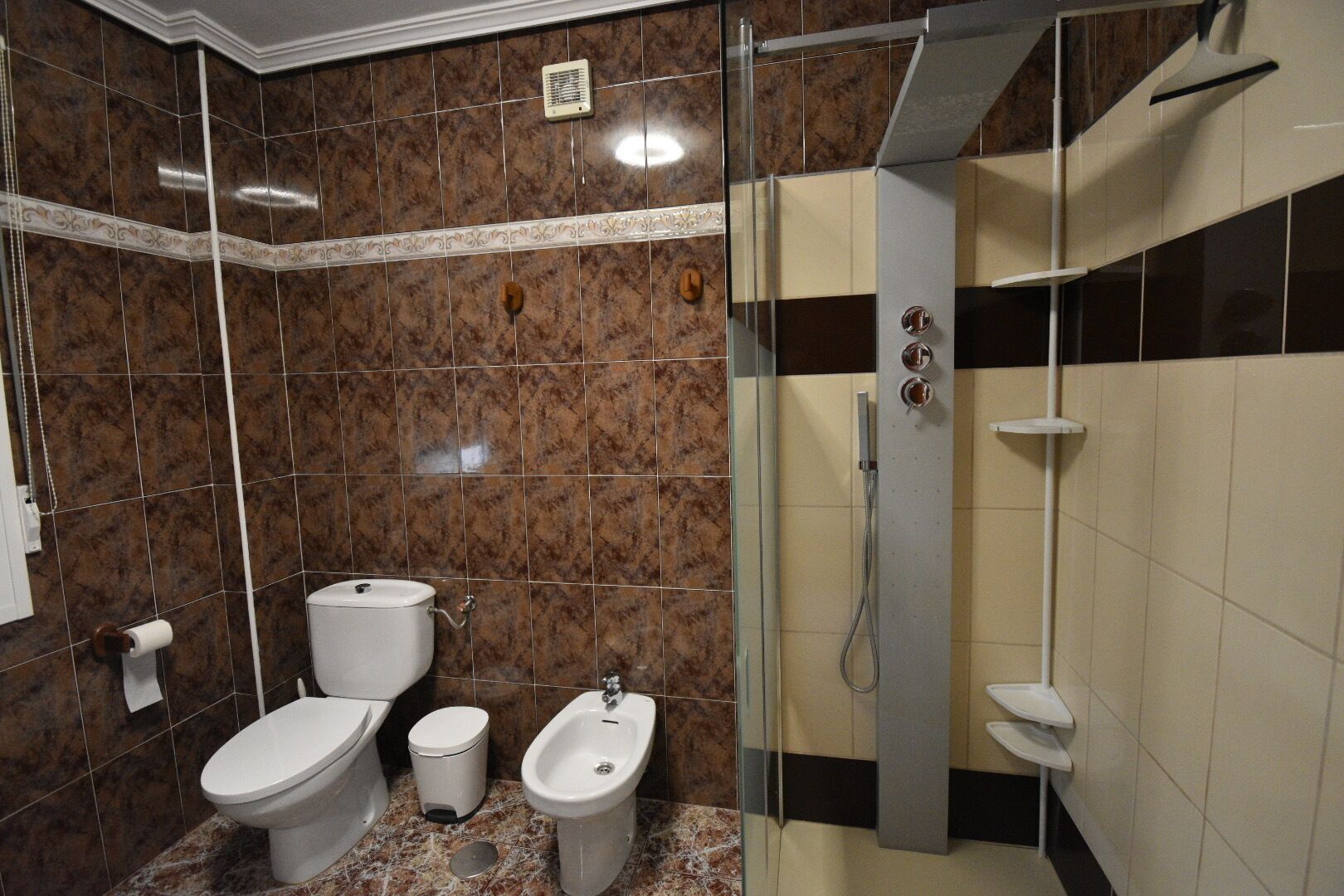 A bathroom with a toilet, bidet, and shower.
