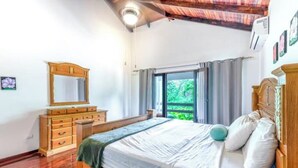 A bedroom with a wooden bed, a dresser, and a window with curtains. - Casa Grande at Flamingo Beach - Family Vacation in Costa Rica (Angeles)