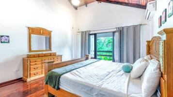 A bedroom with a wooden bed, a dresser, and a window with curtains.