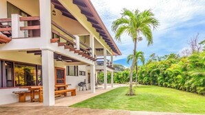 A two-story house with a covered patio, outdoor seating, and a well-maintained lawn. - Casa Grande at Flamingo Beach - Family Vacation in Costa Rica (Angeles)