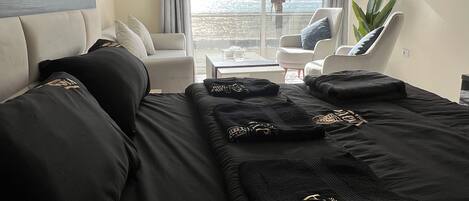 Habitación de hotel con una cama grande, un sofá, una silla y vista al océano.
