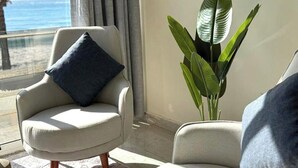 A living room with a view of the ocean, a large plant, and two armchairs. - Voya Hotel and Suites (Tyre)