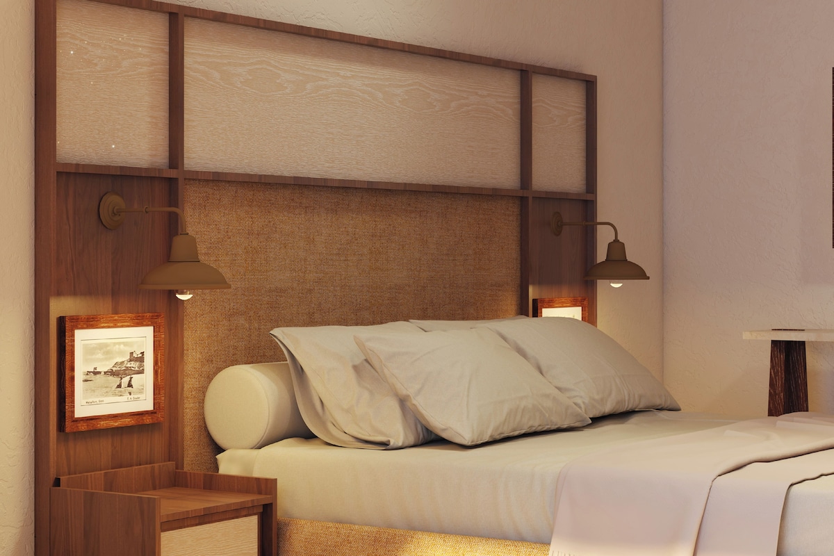 A neatly arranged bedroom with a bed, two bedside lamps, a framed picture, and a small wooden nightstand.