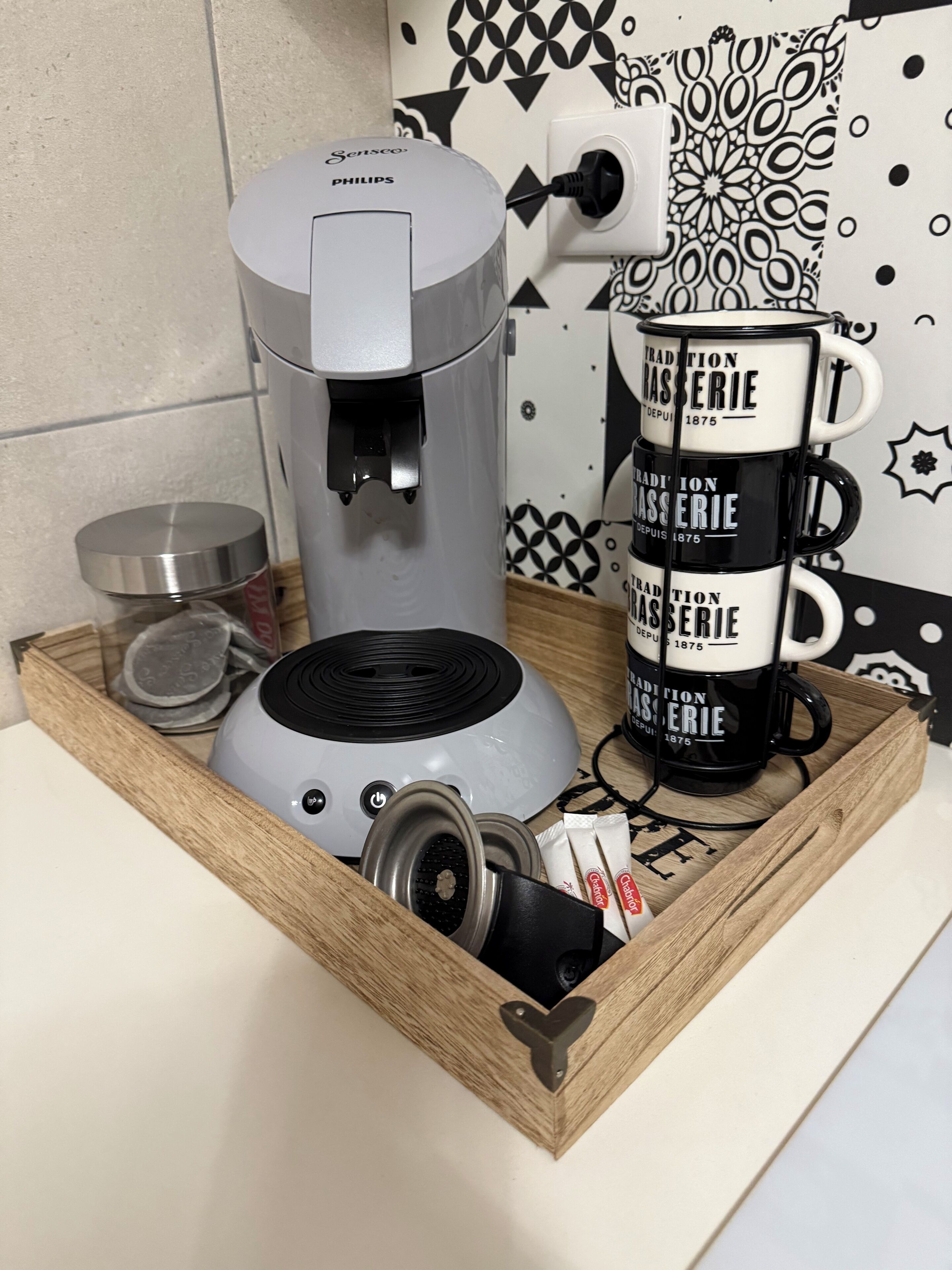 Une machine à café, une tasse et un plateau avec un couvercle et un petit récipient.