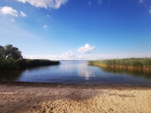 A calm river with sandy banks and dense vegetation on both sides.