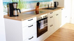 A modern kitchen with a built-in stove, a coffee maker, and a sink. - Apartment Beautiful View (Usedom)