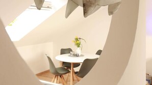 A dining area with a round table and chairs, a hanging fish decoration, and a view of a balcony. - Apartment Beautiful View (Usedom)