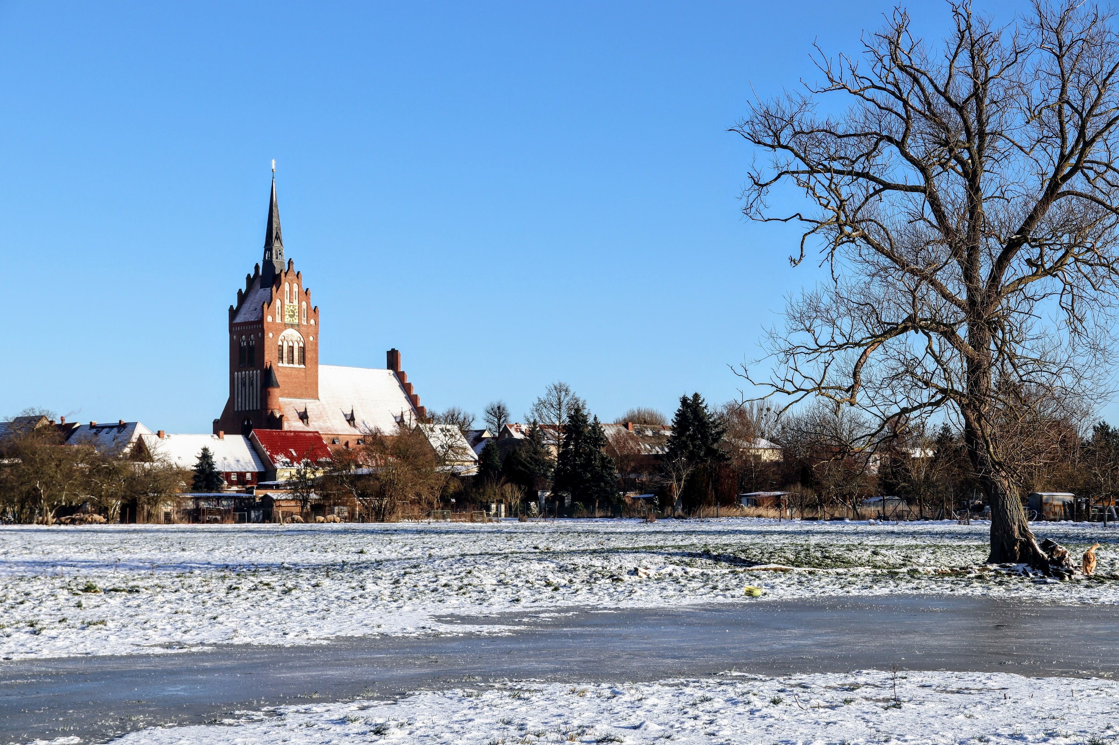 En kyrka med ett högt torn och ett snötäckt fält i förgrunden.