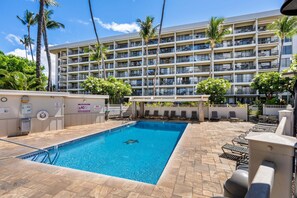 Un hotel con piscina, varios balcones y palmeras.