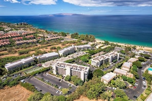 Una zona residenziale sulla costa, con diversi edifici, un parcheggio e una spiaggia sullo sfondo.