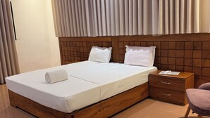 A neatly made bed with a wooden headboard, a nightstand with a drawer, and a chair.