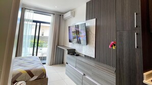 Une chambre d’hôtel moderne dotée d’un grand lit, d’un téléviseur fixé au mur, d’une armoire et d’un balcon avec des rideaux.