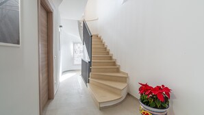 Una escalera con barandilla, una planta en maceta y una puerta a la izquierda.