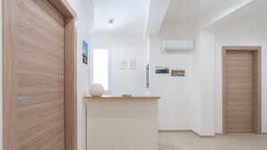 Un interior moderno con un mostrador de recepción, puertas de madera y una pared blanca con un ventanal y una obra de arte.