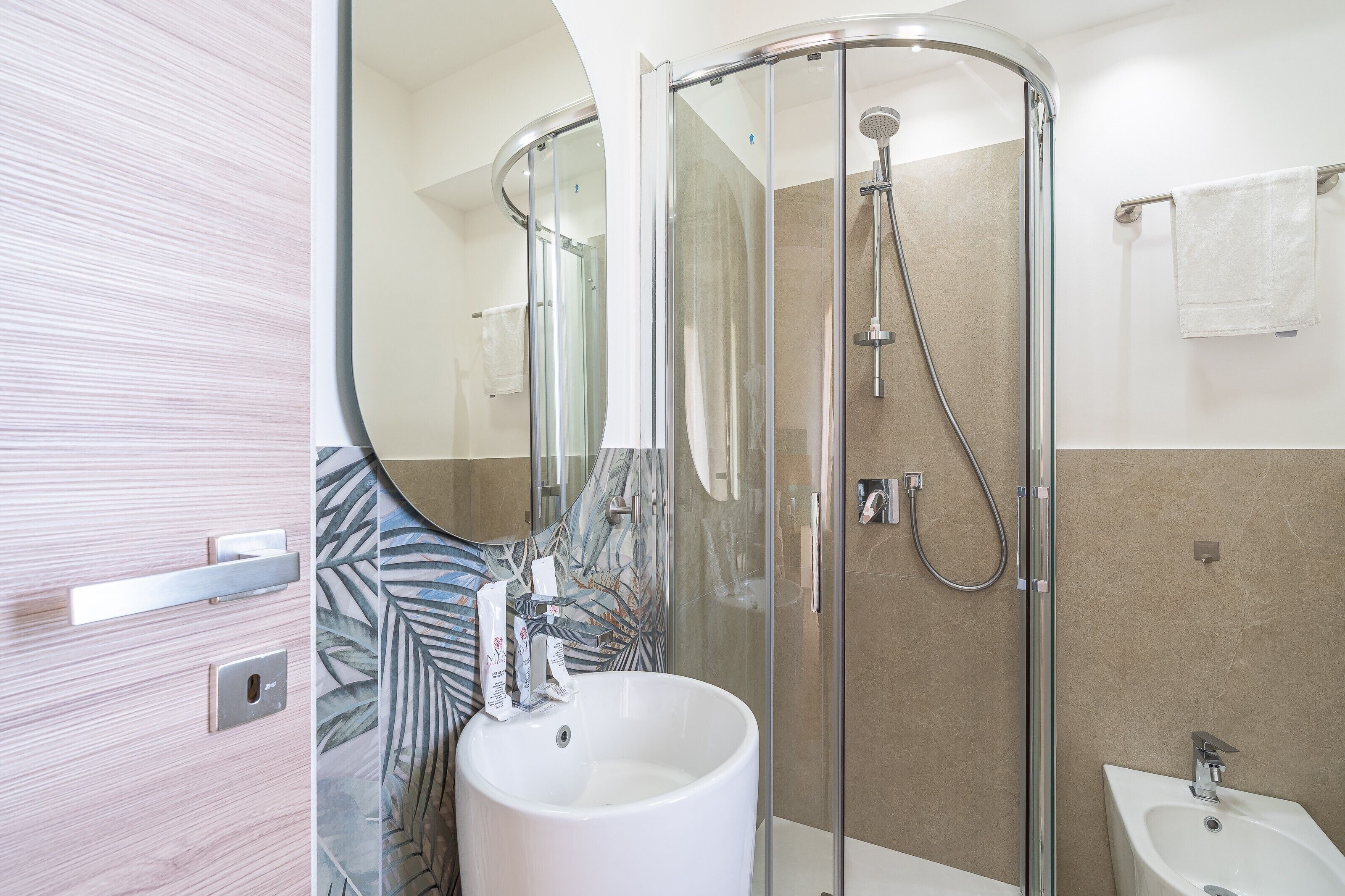 A modern bathroom with a glass-enclosed shower, a sink, and a bidet.