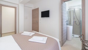 Ein Hotelzimmer mit Bett, Fernseher, Dusche und Toilette.