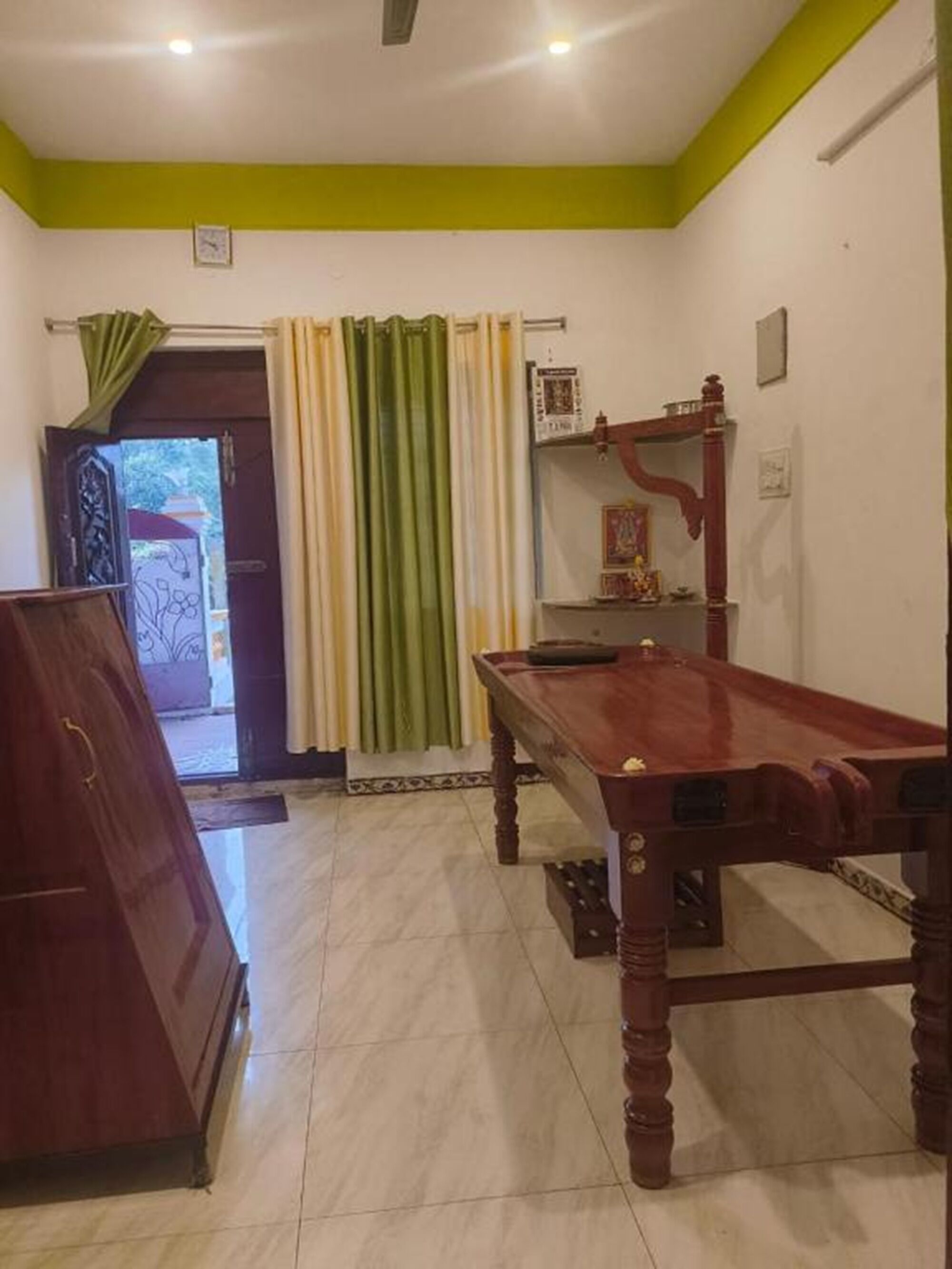 Una habitación con una mesa de madera, un armario y una estantería con objetos decorativos.