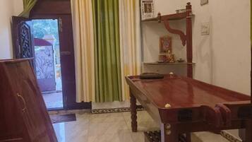 Una habitación con una mesa de madera, un armario y una estantería con objetos decorativos.