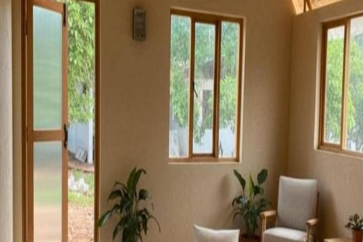 A room with a round seating area, two chairs, and potted plants.