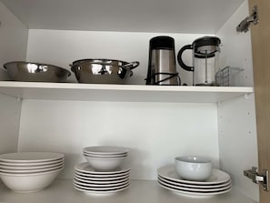 A kitchen with white cabinets, stainless steel cookware, and white dishes. - Welcome to Tasha’s Apartments in Walkerville (Walkerville)