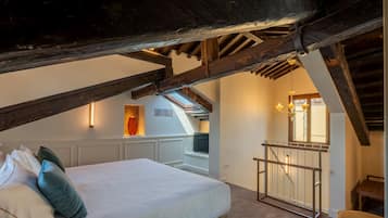 Quarto com cama, almofadas, janela e escada que leva a um andar superior.