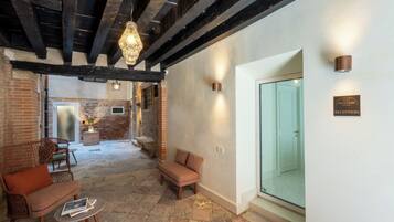 Un área de recepción con piso de piedra, muebles de madera y una puerta de vidrio que da al mostrador.