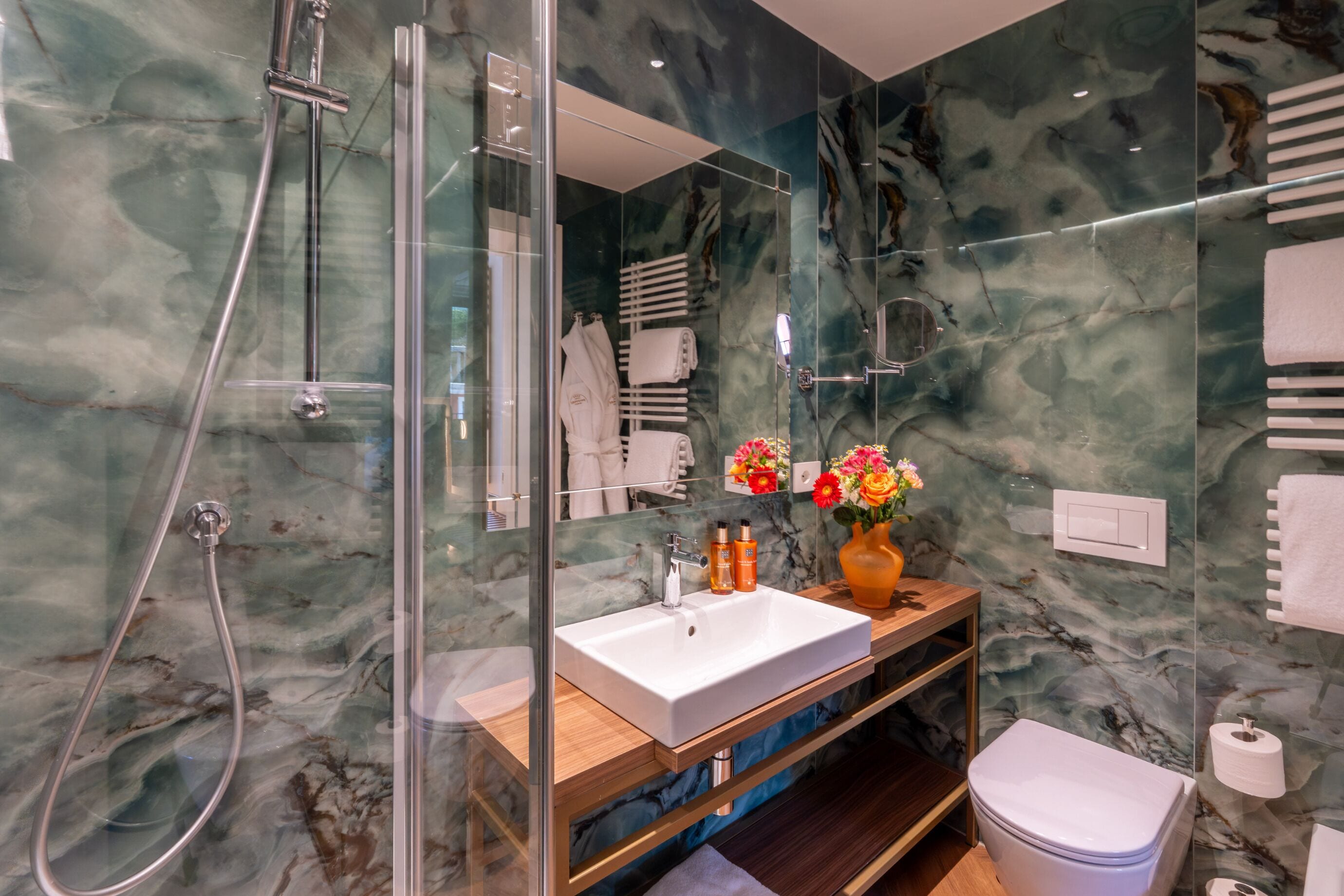 A modern bathroom with a glass-enclosed shower, a white sink, and a toilet.