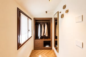 Un corridoio con un'armadio in legno, uno specchio e una porta con finestra.