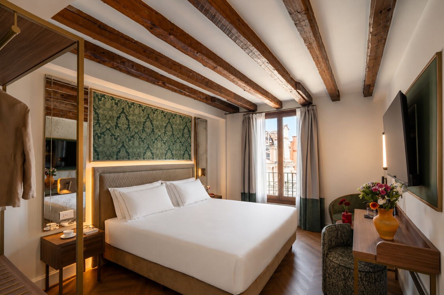 A hotel room with a bed, bedside table, and a view of the city.