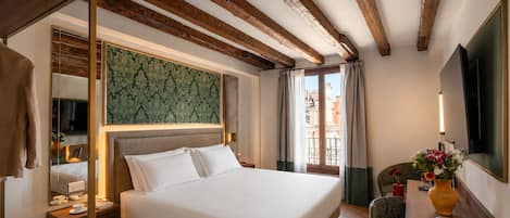 A hotel room with a bed, bedside table, and a view of the city.