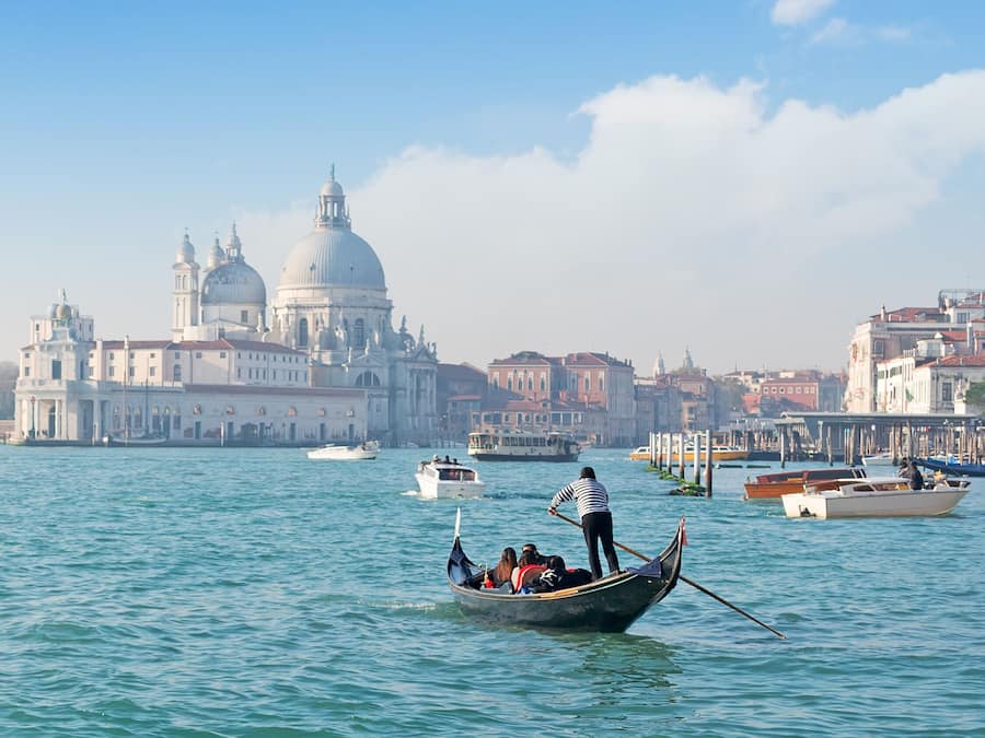 A gondola on Venice's Grand Canal with historic buildings in the background.