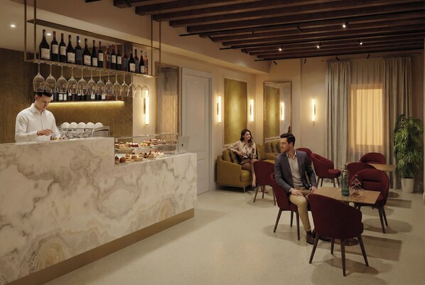 A hotel lobby with a marble reception desk, a bar with wine bottles, and a seating area with red chairs. - Hotel San Samuele (Venice)