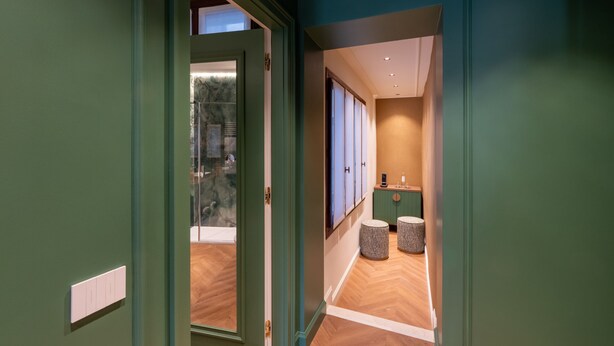 A hallway with a green door, wooden flooring, and a seating area with two stools. - Hotel San Samuele (Venice)