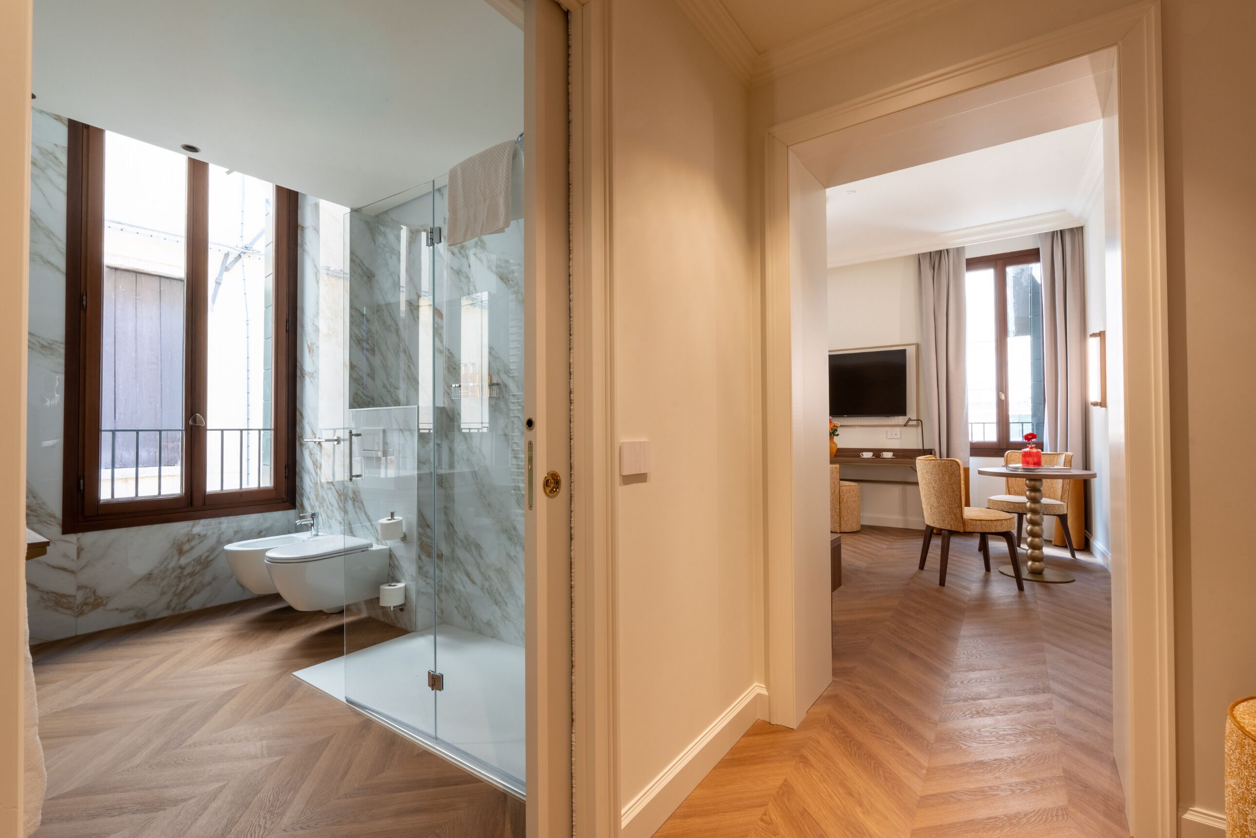 Une salle de bain moderne avec une douche à l’italienne en verre, des toilettes et un pare-baignoire en marbre.