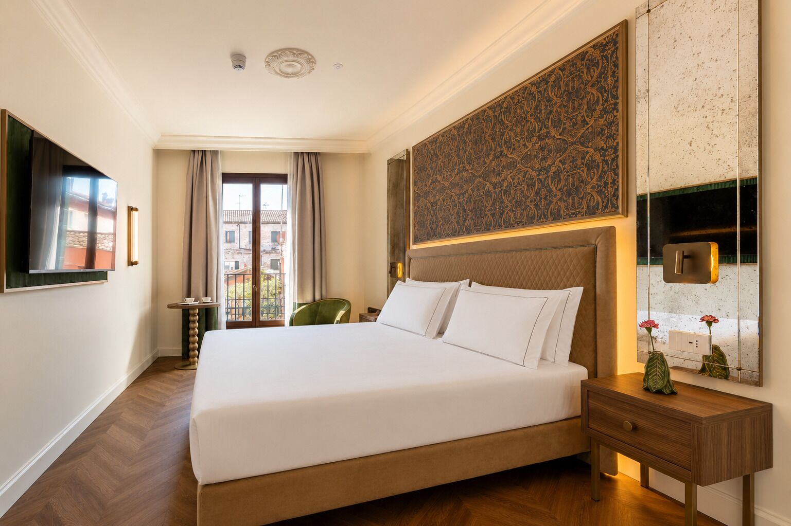 A hotel room with a large bed, a TV mounted on the wall, a small table, and a chair.