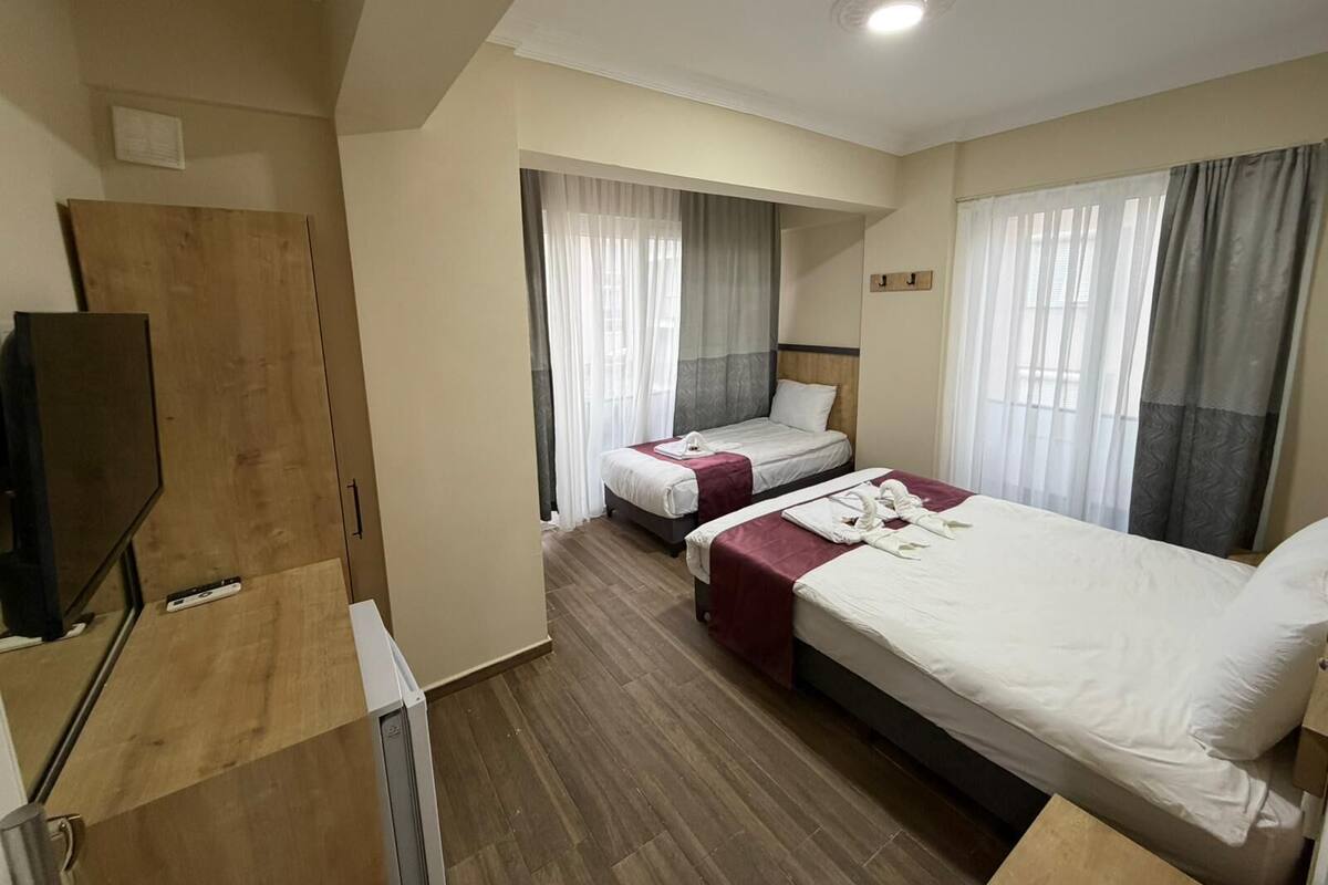 Ein Hotelzimmer mit zwei Betten, einem Fernseher und einem Holzschrank.