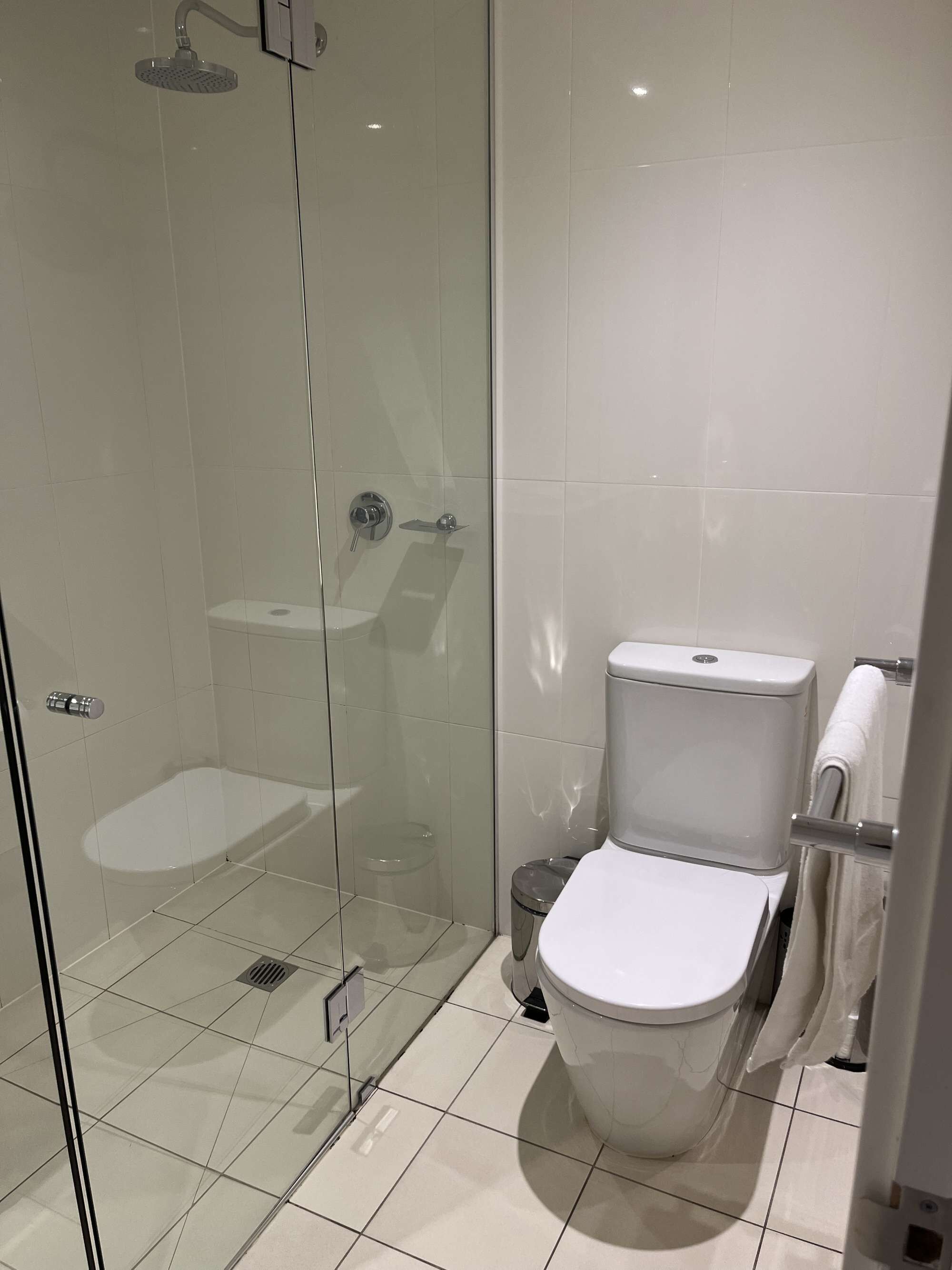 A modern bathroom with a glass-enclosed shower, a toilet, and a glass door.