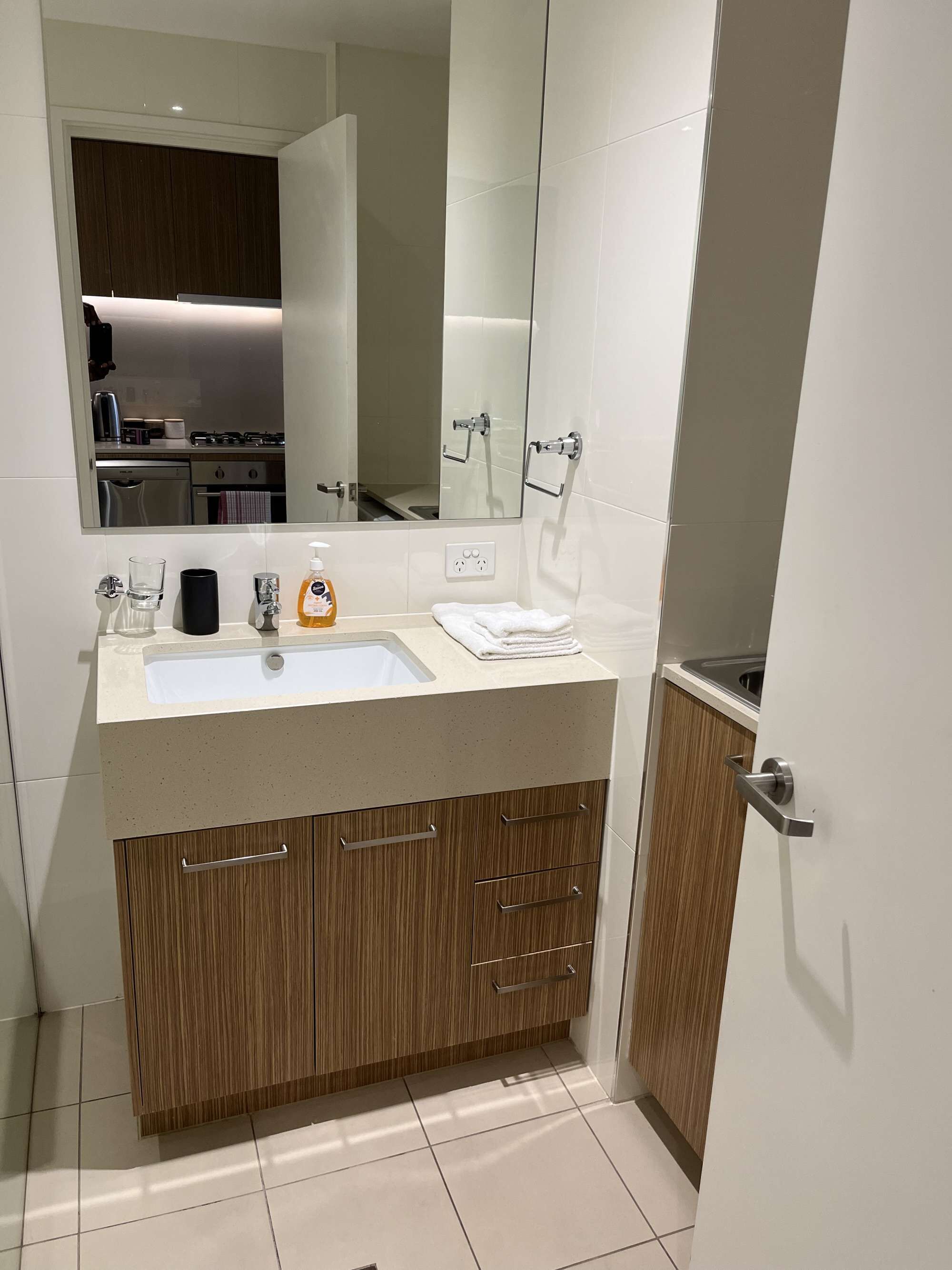 Un bany modern amb un mirall gran, un lavabo i armaris de fusta.