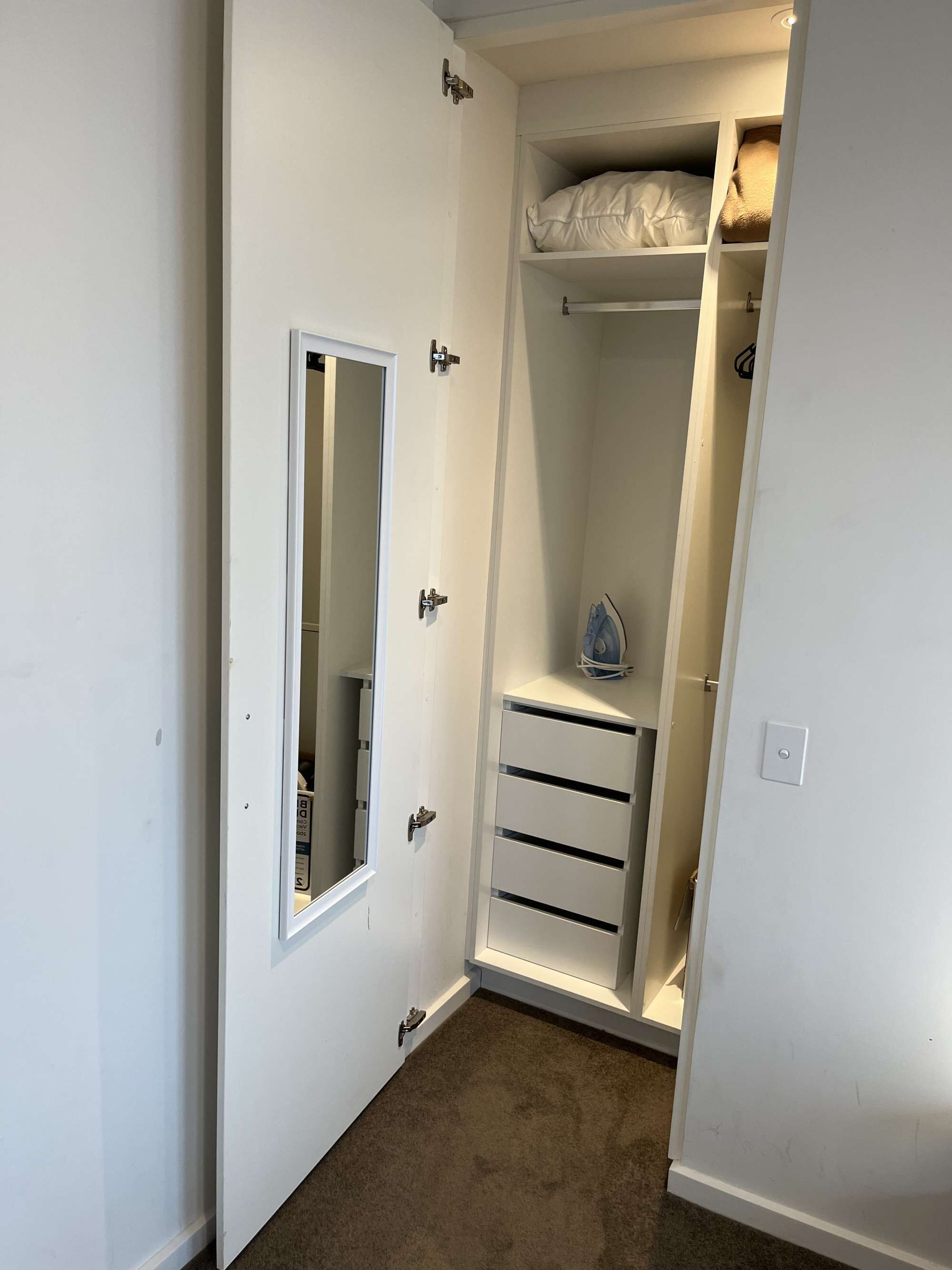 A walk-in closet with a mirror, drawers, and shelves.