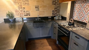 A kitchen with a brick wall backsplash, a stove, and a sink. - Natuur Vakantie Bonte Haan - Het Heerhuys (Berg en Terblijt)