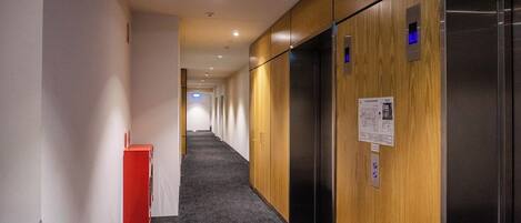 A hallway with wooden paneling, a red cabinet, and an elevator.